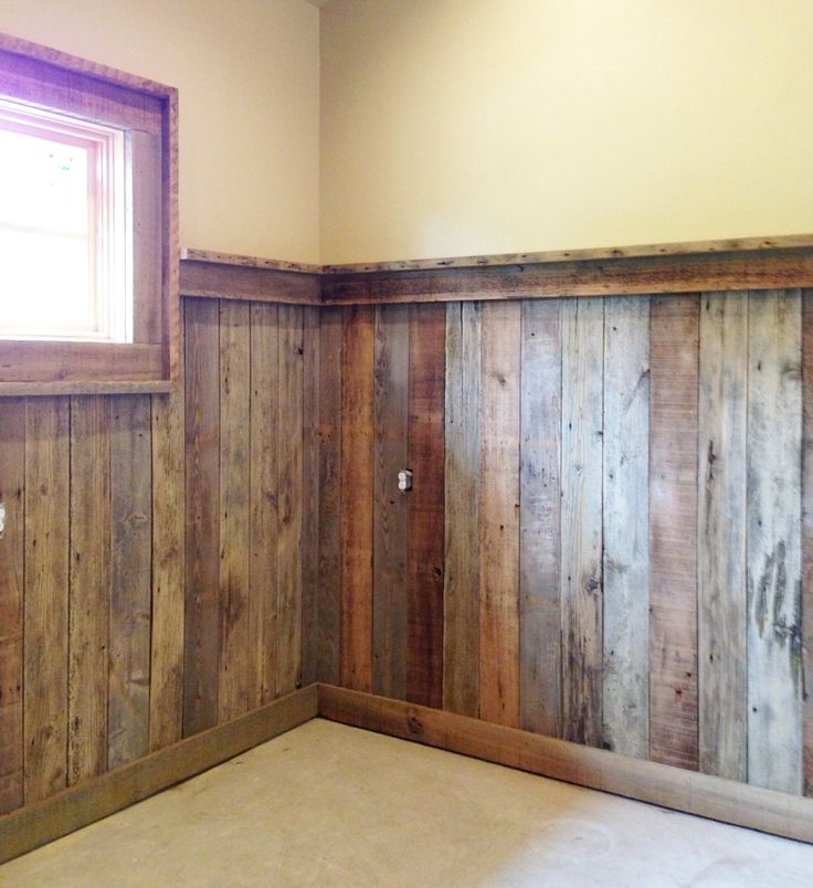 an empty room with wood paneling on the walls and a window in the corner