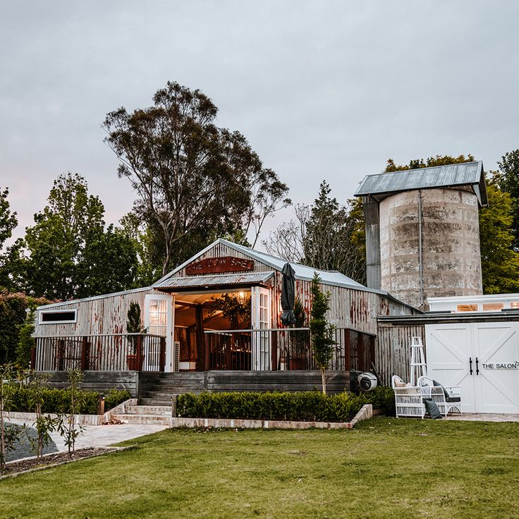 an old farm house with two silos in the back yard and green grass on the front lawn