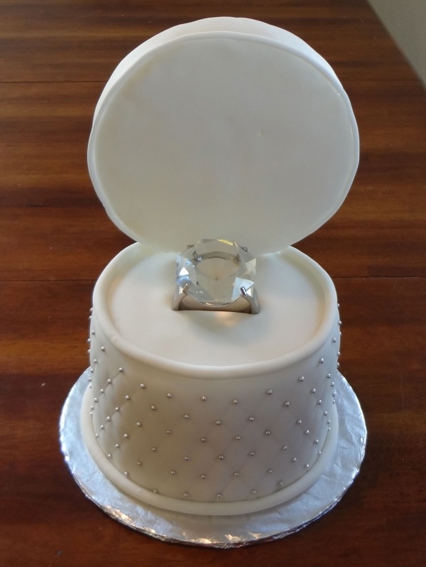 a wedding cake with a diamond ring on top