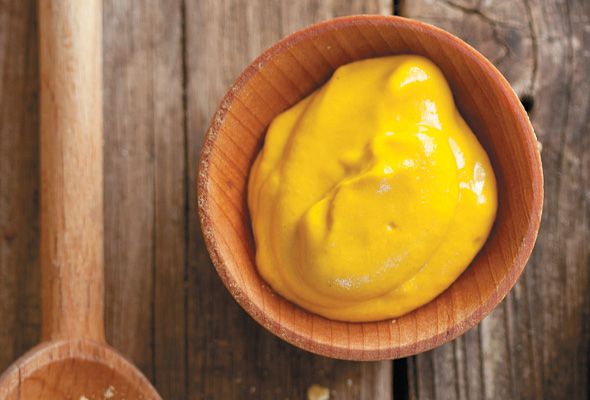 a wooden bowl filled with yellow sauce on top of a table