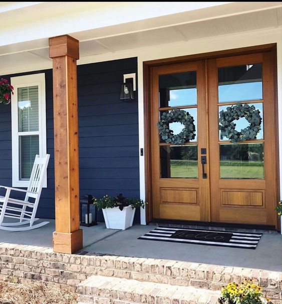 front porch with rocking chair and flower pots on the steps leading up to the front door