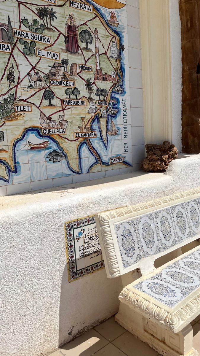 a bench sitting in front of a wall with a map painted on it's side