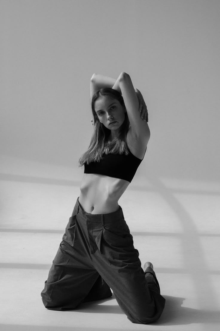 a woman sitting on the ground with her hands behind her head and arms above her head