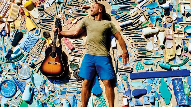 a man standing in front of a wall covered with lots of items