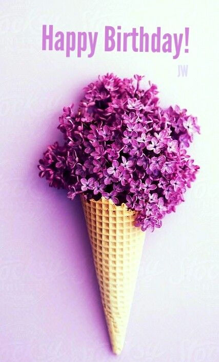 purple flowers in an ice cream cone shaped like a cone on a pink wall background