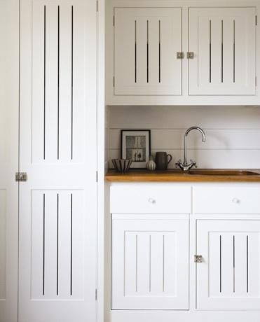 a kitchen with white cabinets and wood counter tops