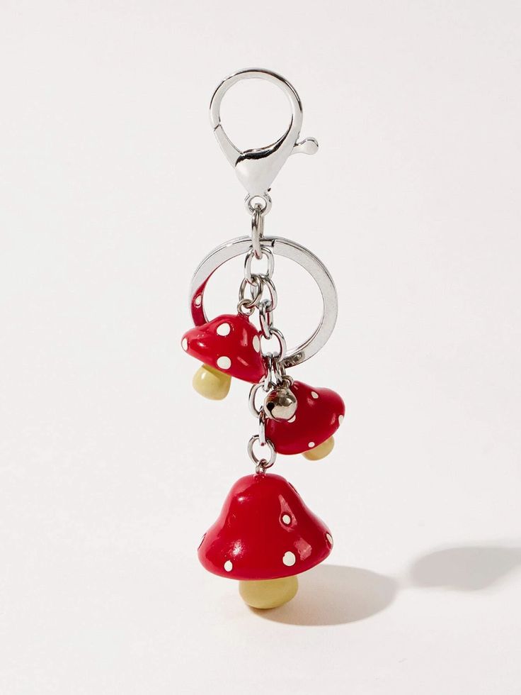 two red mushrooms are hanging from a metal keychain on a white background,