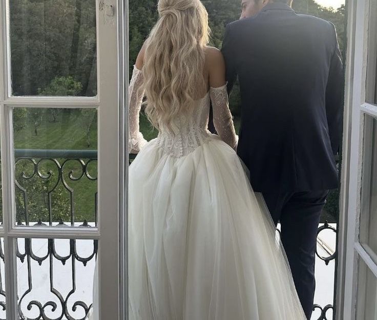 a man and woman in wedding dresses looking out an open door