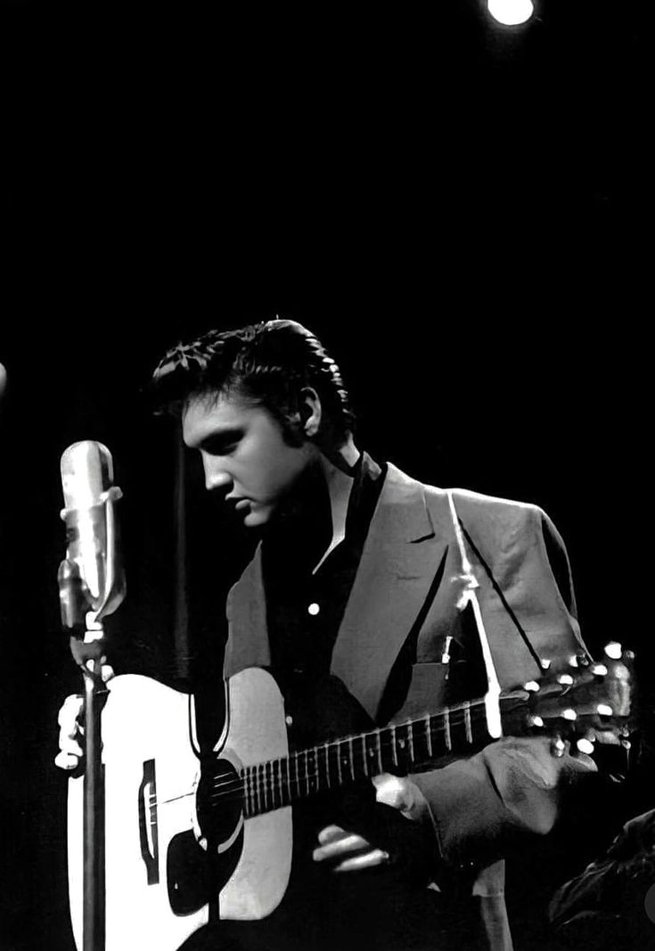 a man holding a guitar in front of a microphone