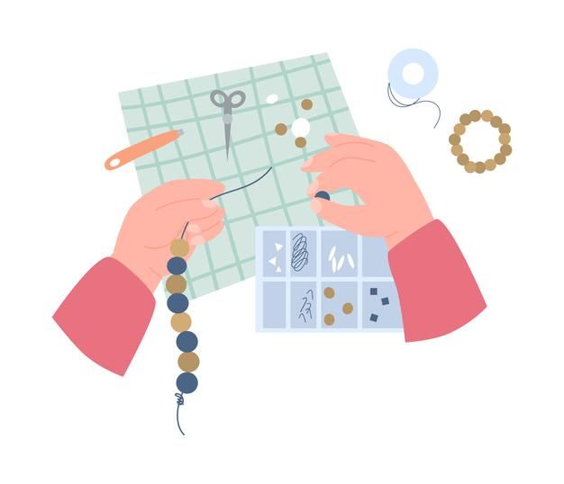 two hands are working with beads and scissors on a piece of paper that is surrounded by other items