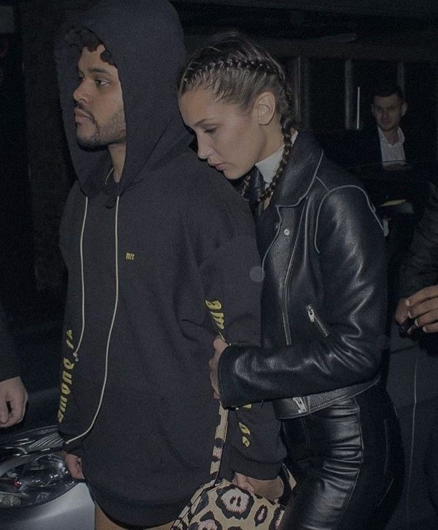 a man and woman are walking together in the dark, with one wearing a black hoodie