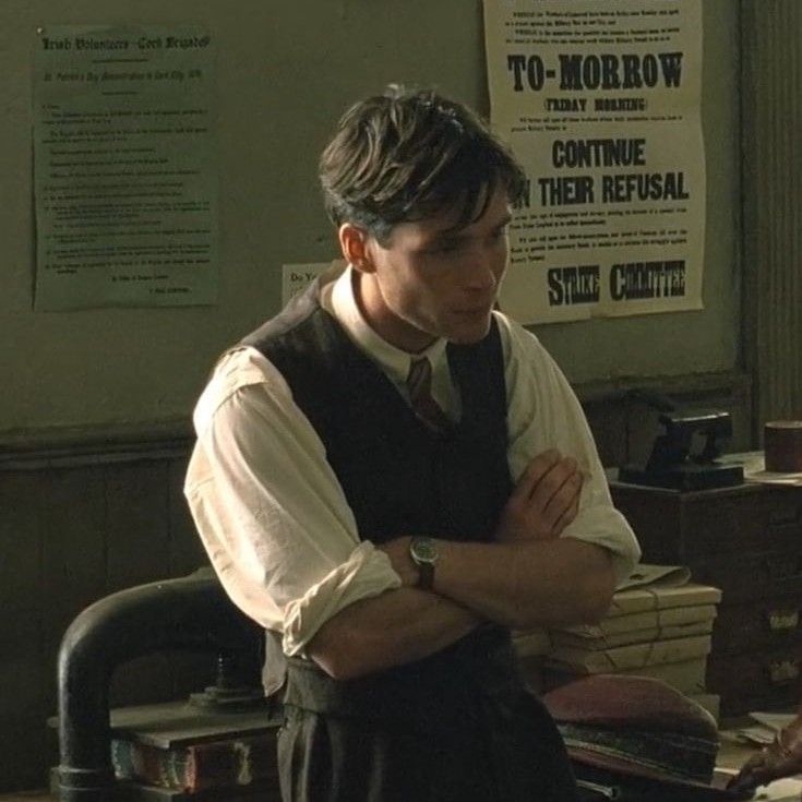 a man standing in an office with his arms crossed and looking at something on the desk