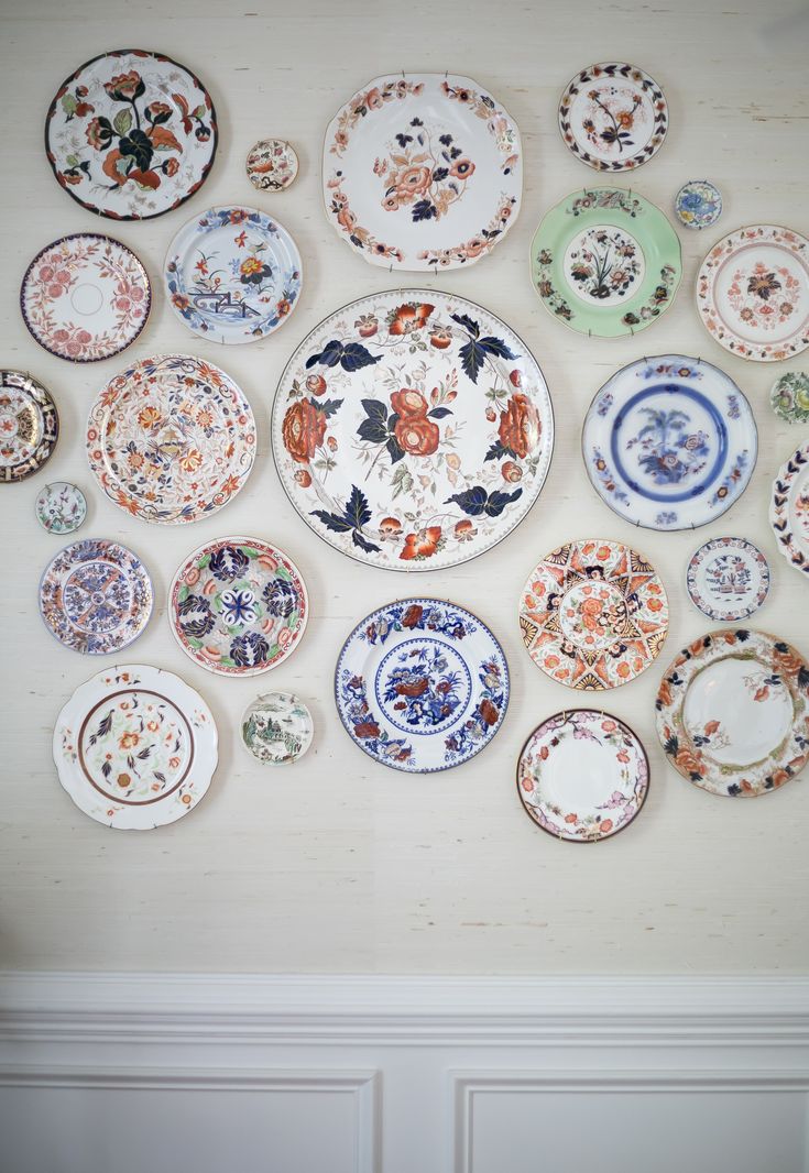 many plates are arranged in the shape of a flowered circle on a white wall