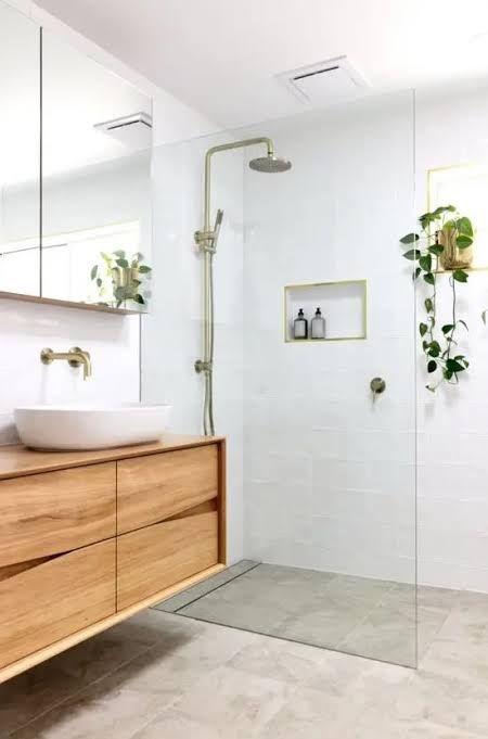 a bathroom with a sink, mirror and shower in it's center wall next to a wooden cabinet