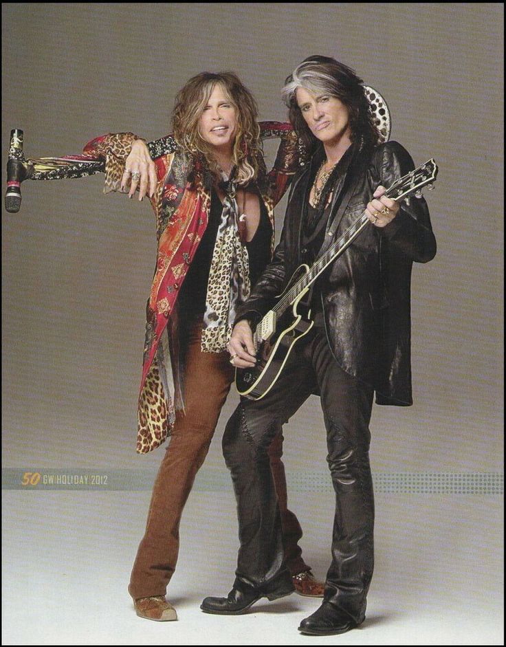 two people standing next to each other holding guitars