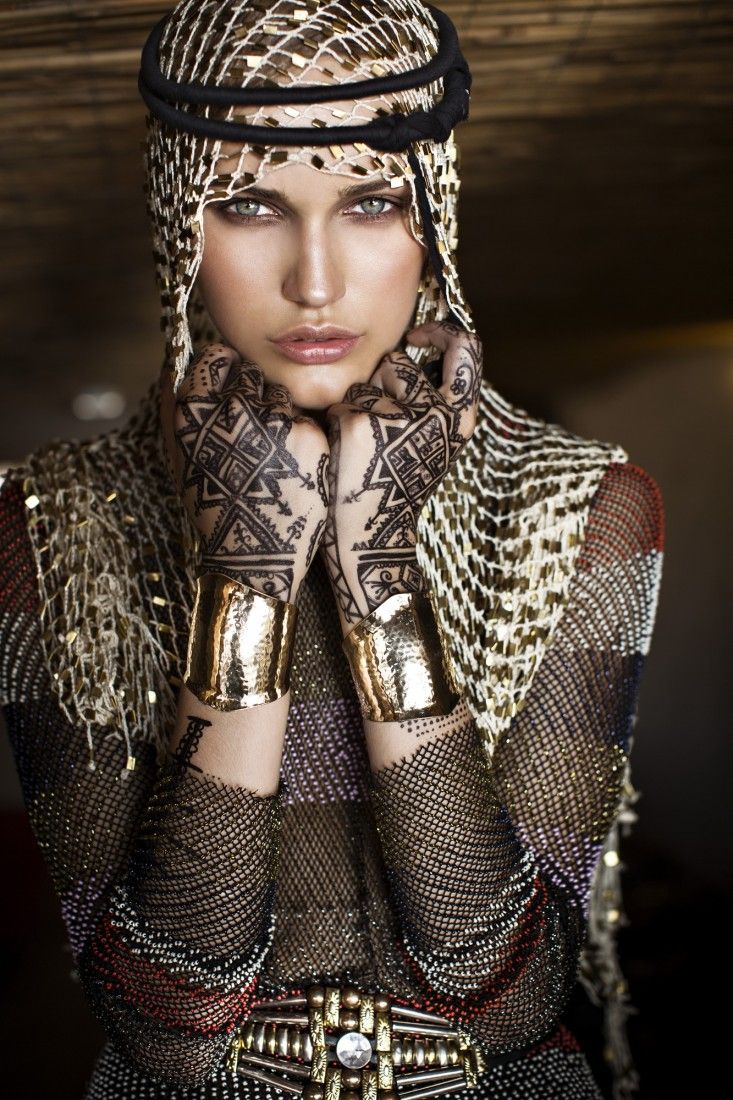 a woman with tattoos on her arms and hands is posing for the camera, wearing gold gloves