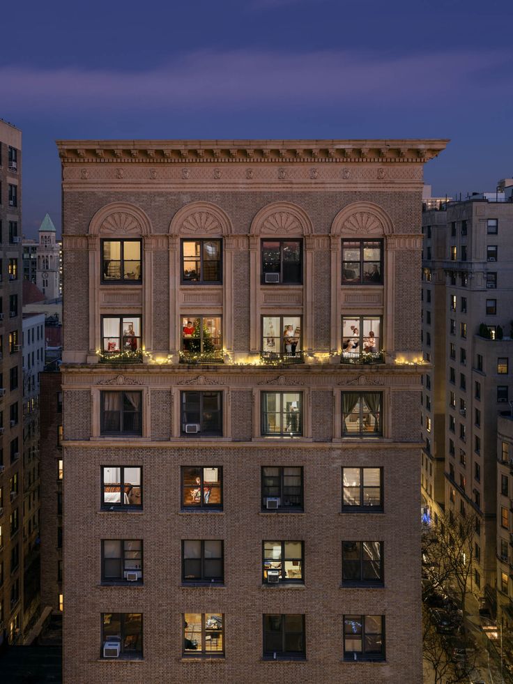 an apartment building is lit up at night with christmas lights on it's windows