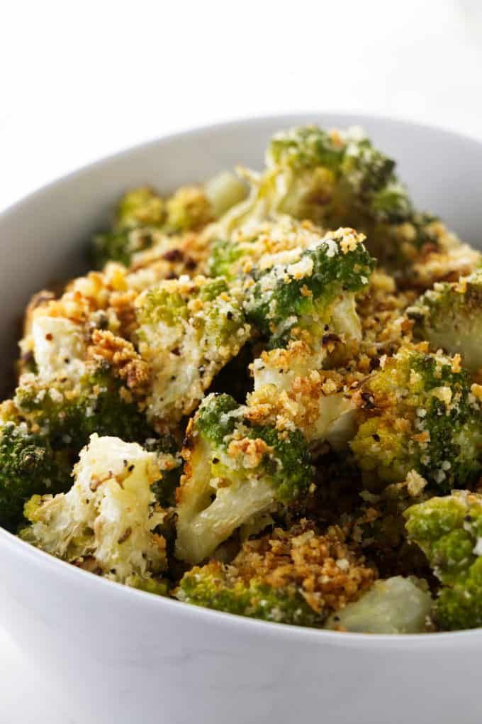 a white bowl filled with broccoli covered in crumbs and seasoning