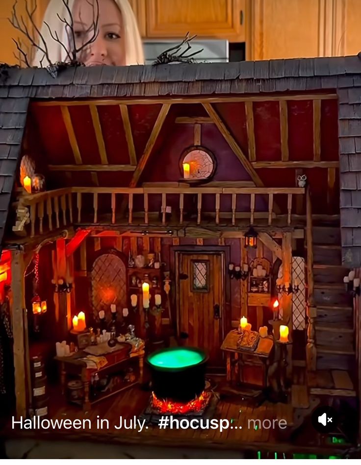 a doll house is shown with candles in front of it and a woman looking out the window