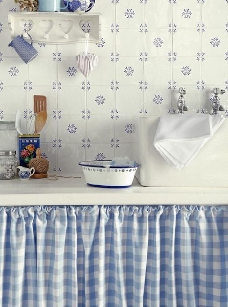 a kitchen with blue and white wallpaper, dishes on the counter and hanging utensils