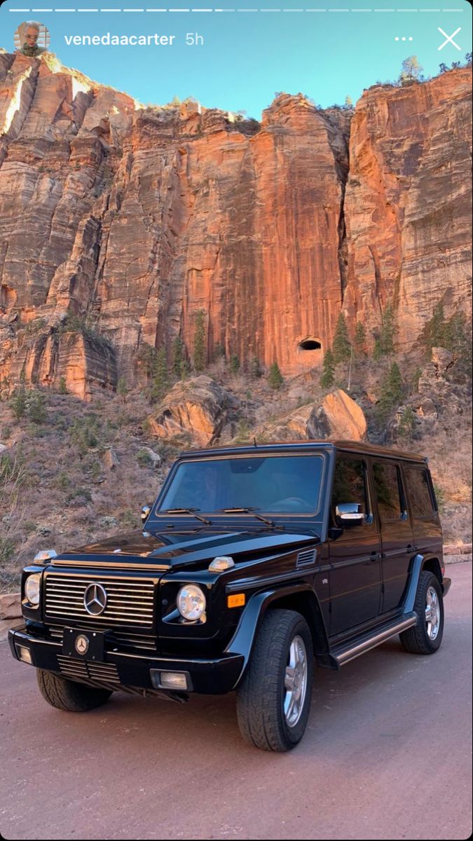 a black mercedes g - class parked in front of a mountain with the caption send message