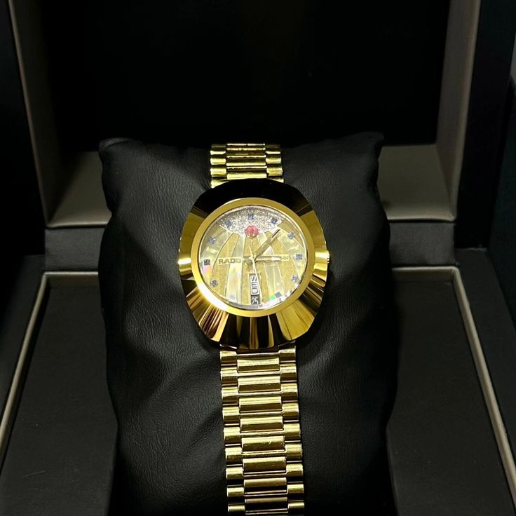 a gold watch sitting on top of a black pillow