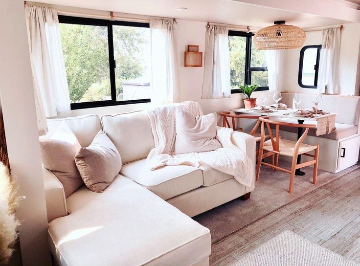 a living room filled with furniture next to a table and window covered in white curtains