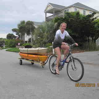 a woman riding a bike with a trailer attached to it