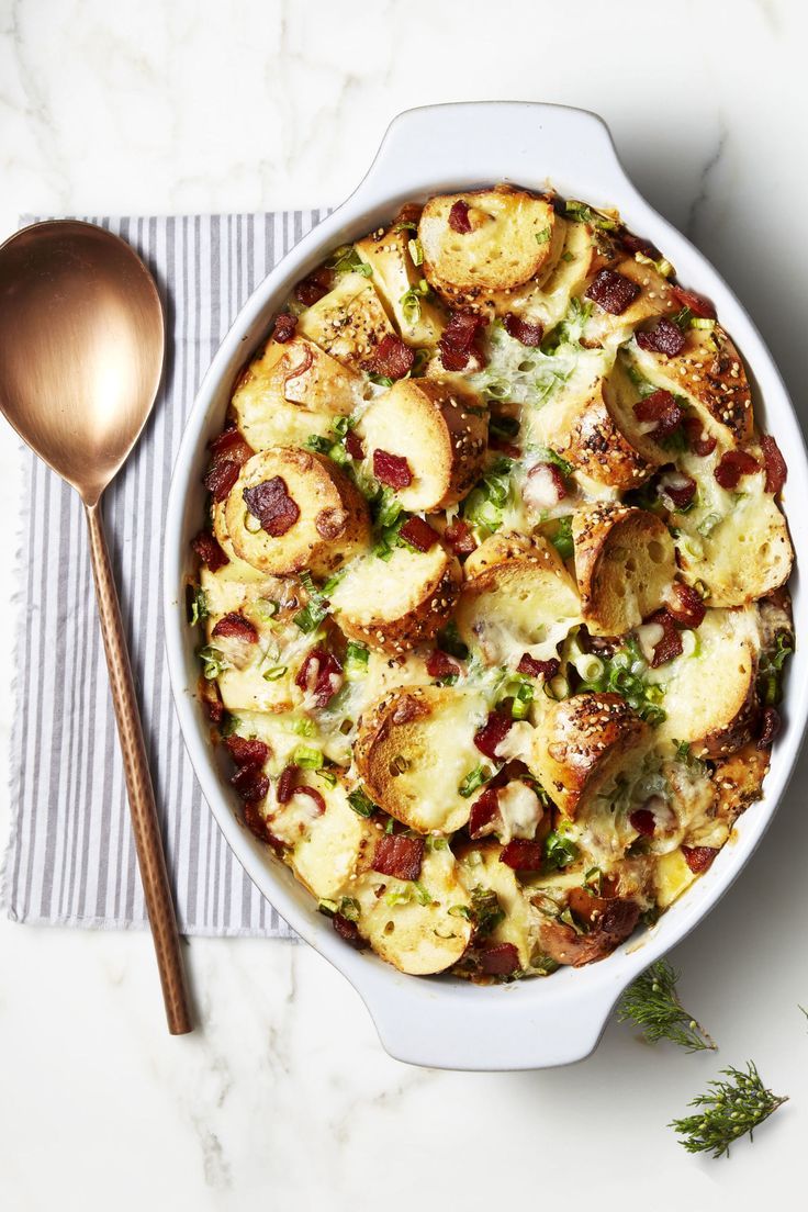 a casserole dish with potatoes, broccoli and other toppings next to a spoon