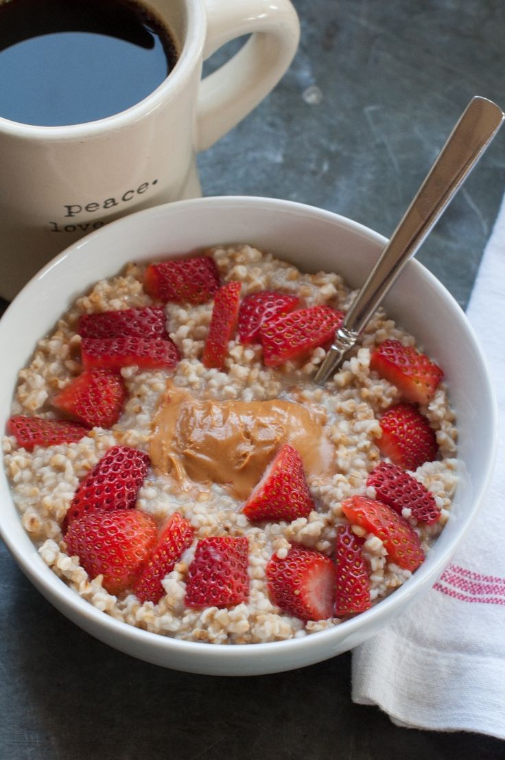 a bowl of oatmeal with strawberries and peanut butter on the side