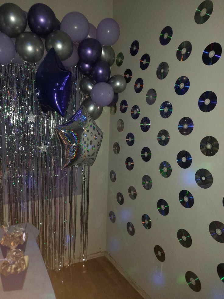 balloons and streamers are hanging from the ceiling in this room with disco - themed wallpaper