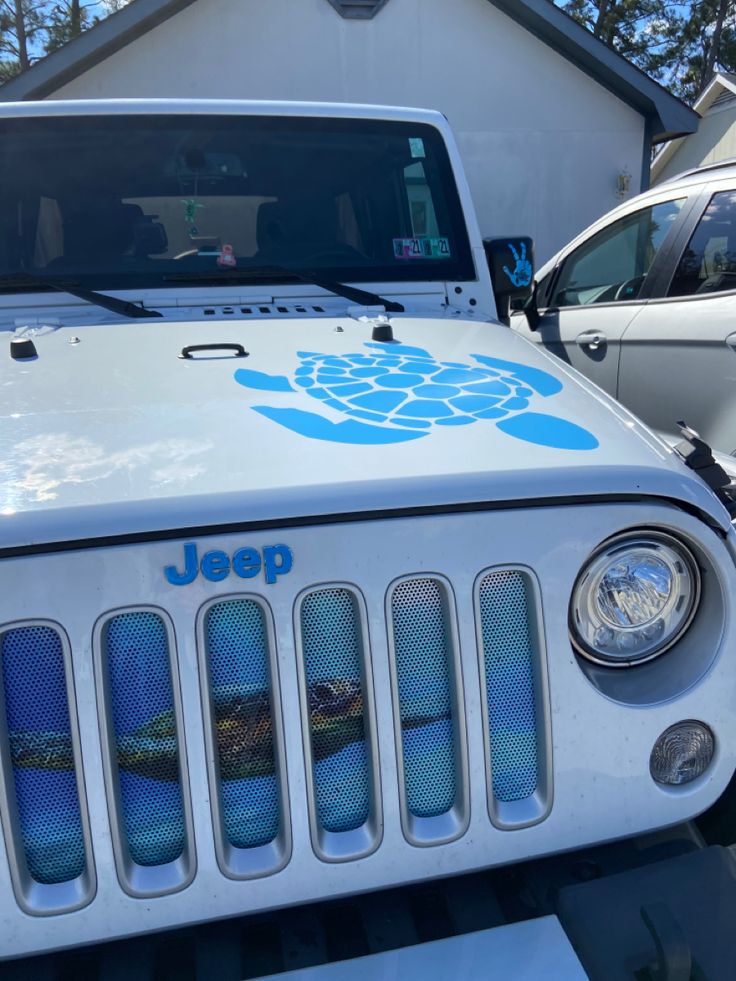 a jeep parked in front of a house with a turtle decal on the hood