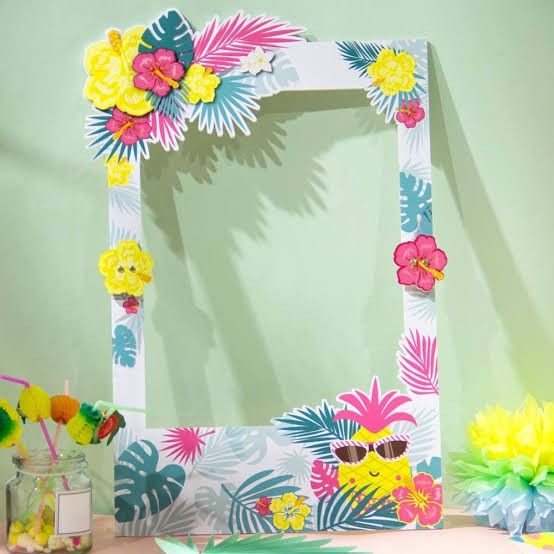 a white frame decorated with colorful flowers and leaves on a table next to a jar