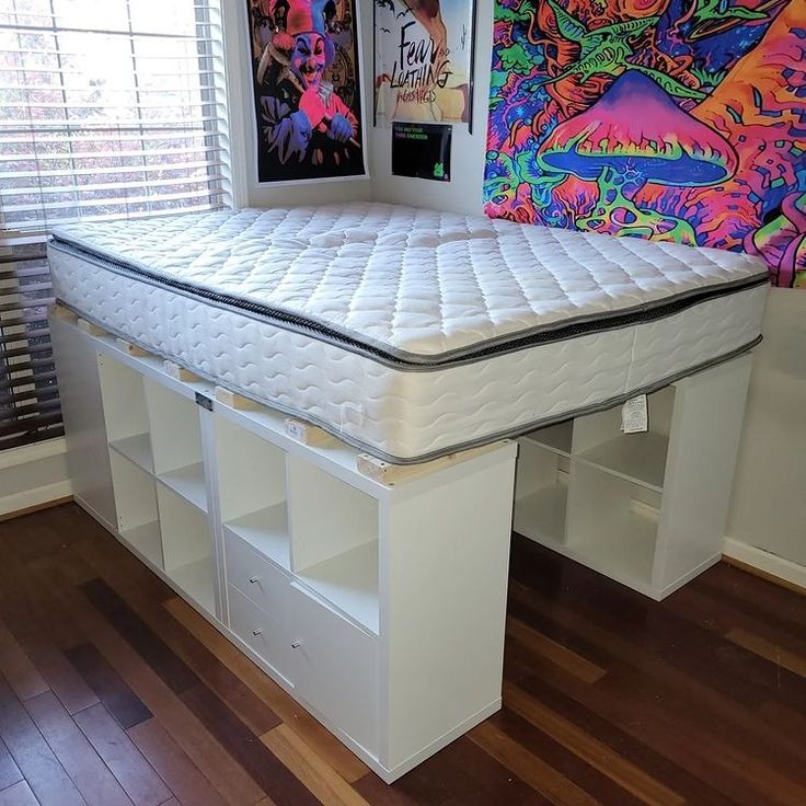 there is a bed that has been made with white mattresses and drawers on it