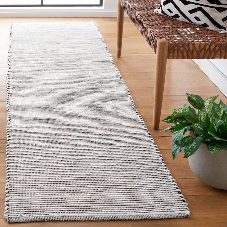 a large white rug in a living room next to a chair and potted plant