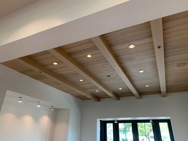 an empty room with wooden ceiling and windows