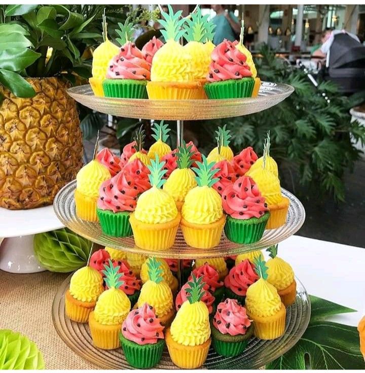 three tiered trays filled with cupcakes and pineapples