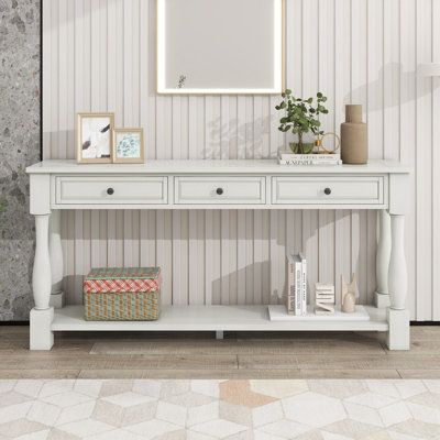 a white console table with two drawers and a mirror on the top, against a striped wallpapered background