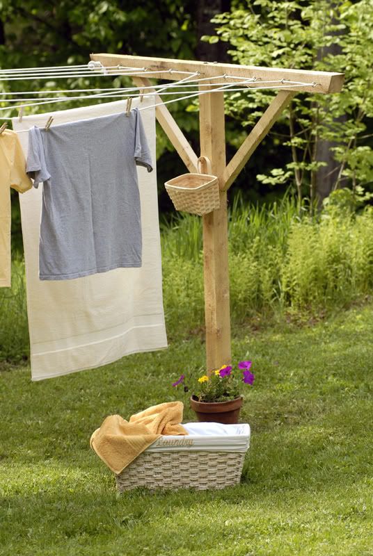 clothes hanging out to dry on a clothes line in the grass with flowers and potted plants