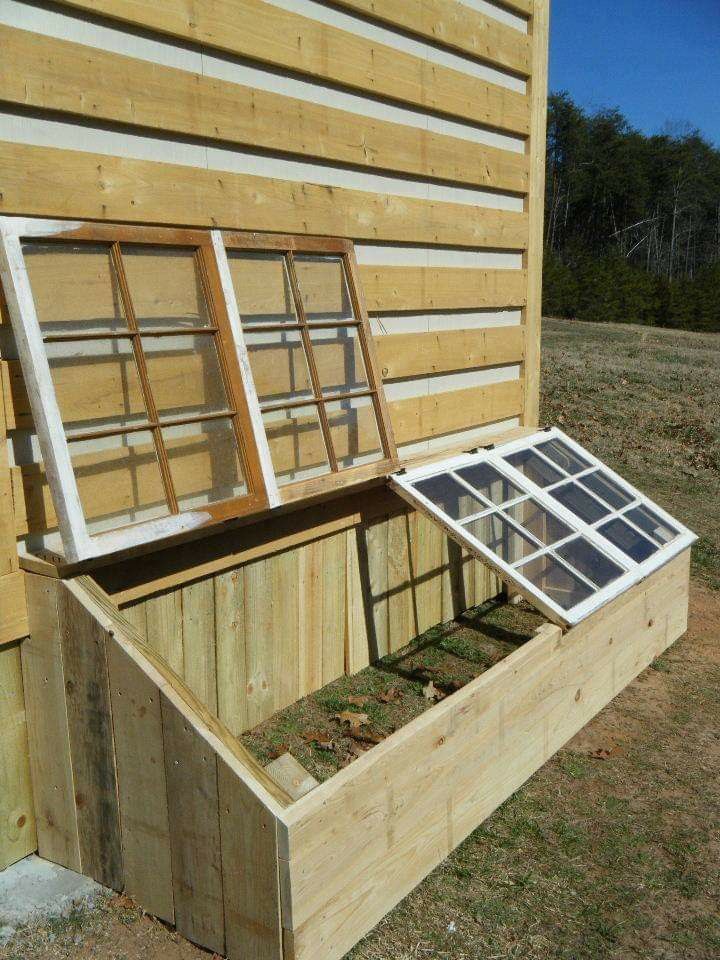 an open window on the side of a wooden building with grass growing inside and outside