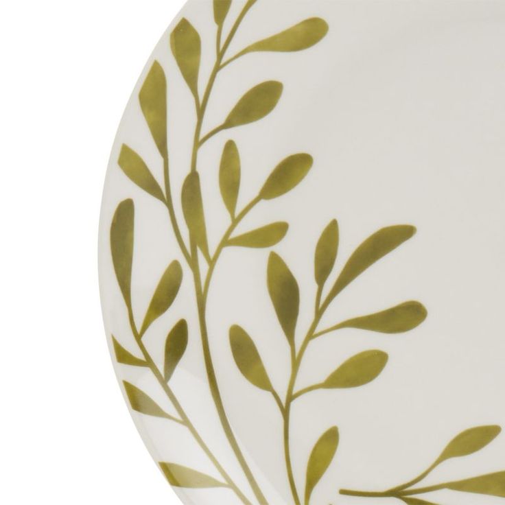 a white plate with green leaves painted on the front and back side, in an elegant manner