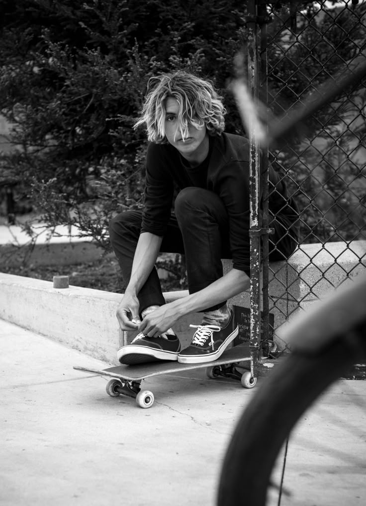 a man riding a skateboard down the side of a cement wall next to a fence