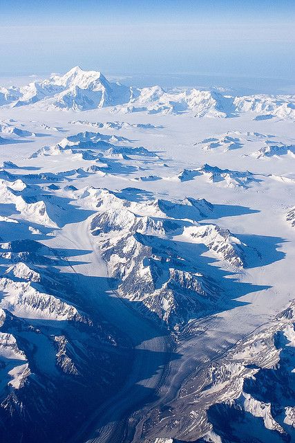 an aerial view of snow covered mountains and valleys