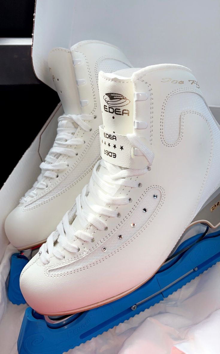 a pair of white ice skates sitting on top of a blue and white box