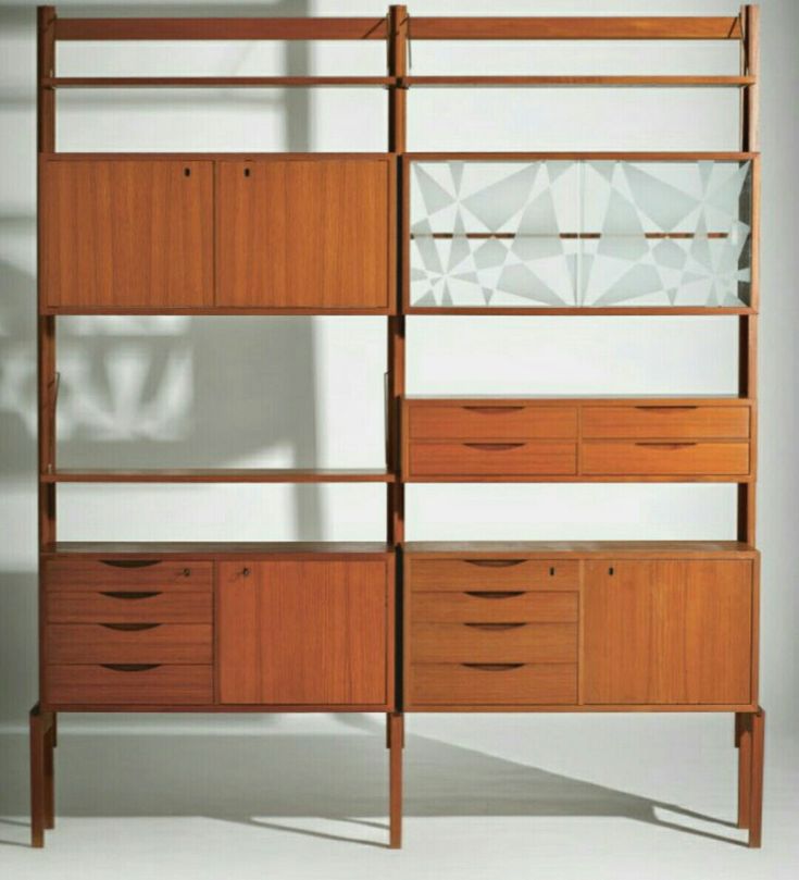 a wooden bookcase with drawers and glass doors on the front, against a white wall