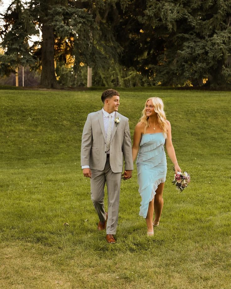 a bride and groom walking through the grass