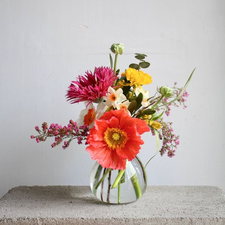 a vase filled with lots of different colored flowers