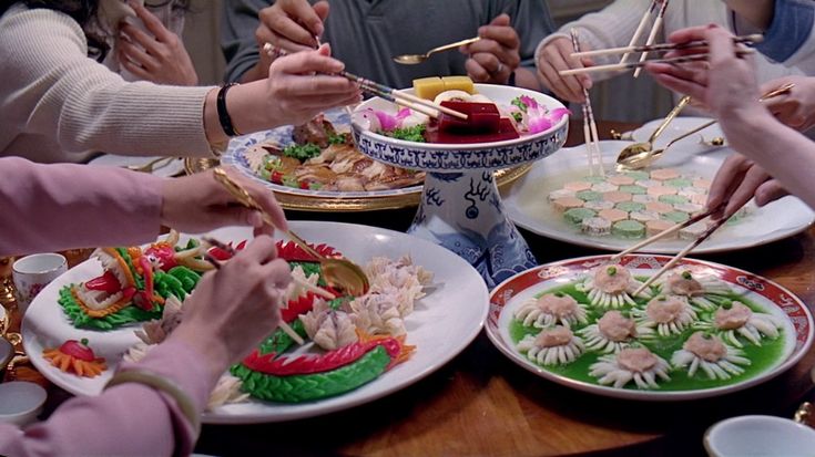 several people are serving themselves food at a dinner table with chopsticks in their hands