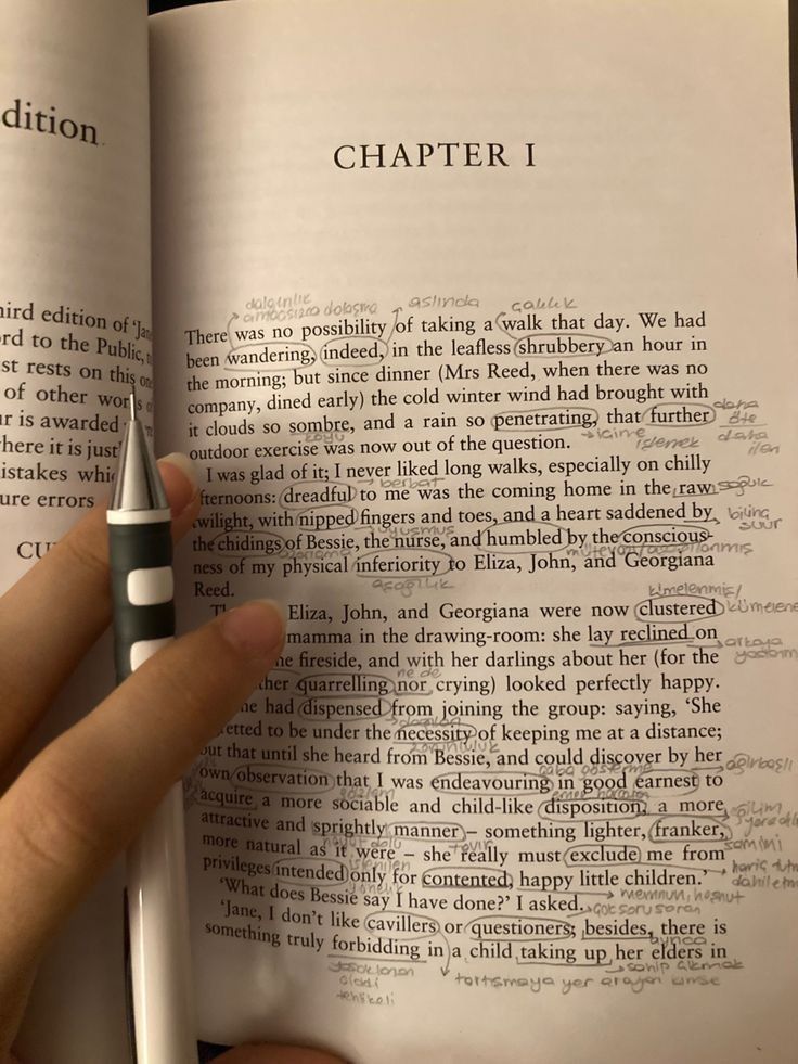 a person holding a pen in their hand over an open book with the title written on it