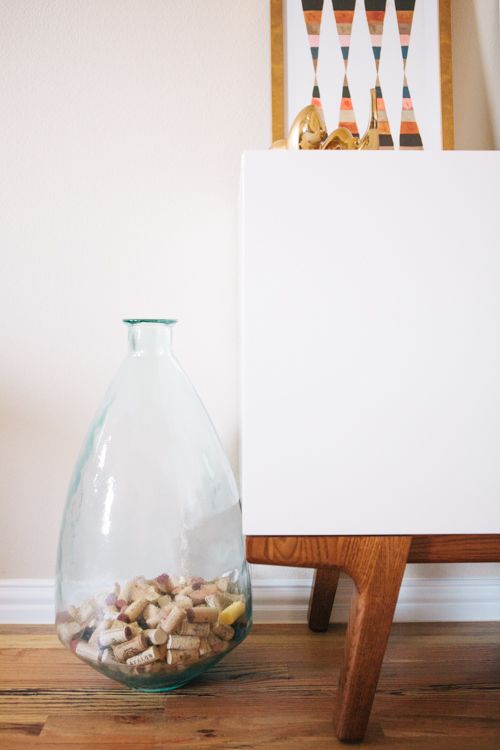 there is a glass vase with nuts in it next to a white board on the floor